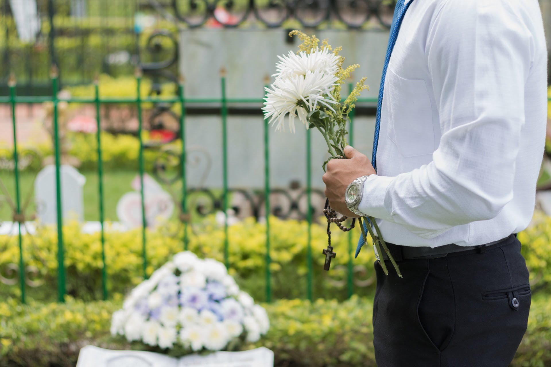 Man holding flowers at a funeral standing near casket