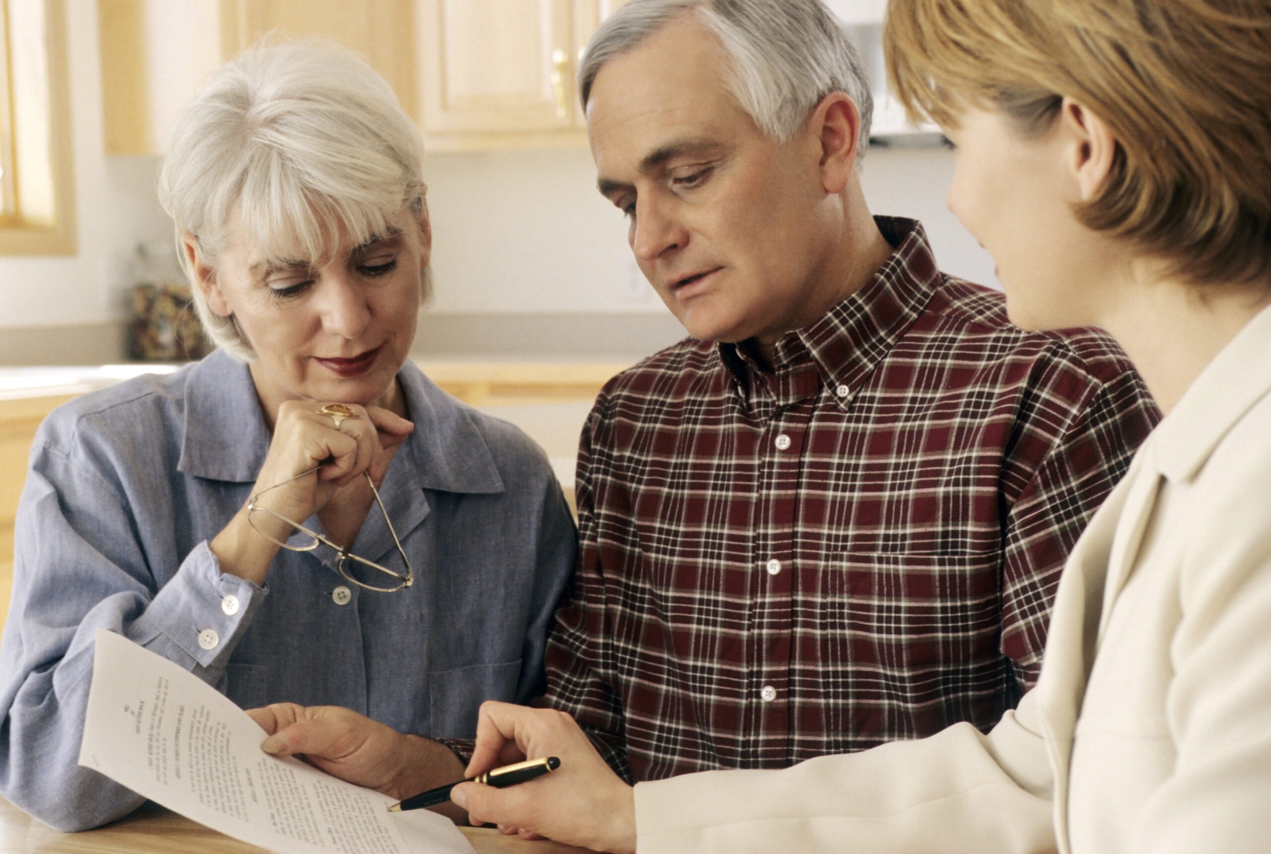 Mature couple talking to funeral planner at home about prepaid funerals