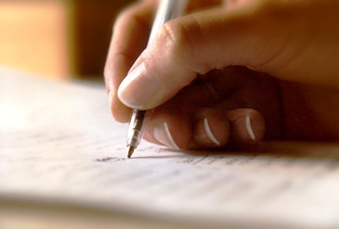 Closeup of a person's hand writing - paying for a funeral